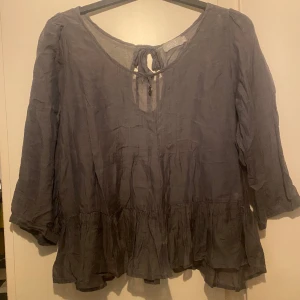 Grå sidenblus strl M/L - Vacker kocksgrå blus trekvartsärm, volanger längst ner, från Ajlajk. Oanvänd!  Storlek M/L