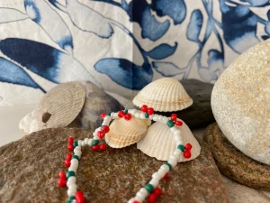 Armband gjord av pärlor med körsbär - Armbandet är gjord med kärlek och tålamod. Armbandet har körsbär som hänger ner runt hela. Körsbären är gjorda av gröna och röda pärlor.  Är slitstark och till att badas och duschas med.