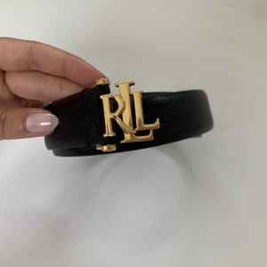 Ralph Lauren skärp - Ett äkta ralph lauren skärp med guldspänne. Helt i nyskick! Svart skinn, smal och elegant rämm. 