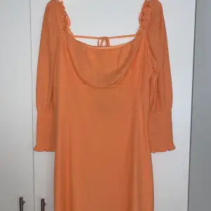 En orange klänning i pliserat material, med en väldigt vacker öppen rygg🌼