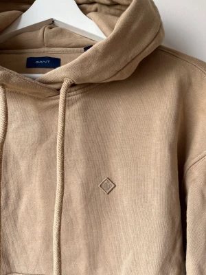 GANT ICON hoodie - Hoodie i boxig modell med stor tjock luva. Använd två gånger sen legat i en påse efter tvätt, och därför lite skrynklig.. men i väldigt gott skick!