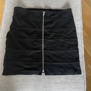 Svart kjol med dragkedja  - En svart kjol med dragkedja på framsidan, knappt använd. 