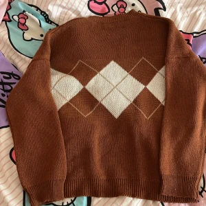Brun rutig stickad tjocktröja - Säljer pga att jag inte har använt den. Helt nytt skick. Bild 1 är framsidan av tröjan, Bild 2 är bak sidan. Är du intresserad/vill ha fler bilder/har frågor så kontakta mig. 