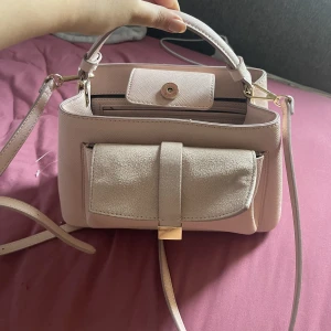 Väska - Babyrosa väska i mycket fint skick, använt 1 gång och rymmer mycket. 3 fack på insidan och ett fack på utsidan. 