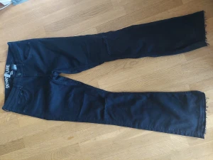 Utsvängda jeans hög midja - Mycket hög midja, något slitna av användning. Femficksmodell. Fransiga benslut och upprivna knän från fabrik. Stretch och något slimmande effekt. Passar strlk S-M.
