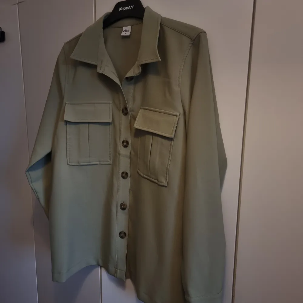 Ljus militärgrön skjortjacka från Ellos. Med knytning i midjan. Storlek 38. Skjortor.