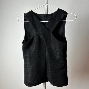 Blus med kryss framtill - Fin blus med innertyg och dragkedja i ryggen. Jättefin till ett par kostymbyxor! Säljer pga för liten. Från MQ (deras märke Zoul)