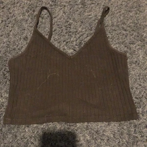 Linne - Svart ribbat linne, V ringning, stretchigt material, knappt använd, är helt svart i verkligheten (ser grå/brun ut på bild)