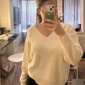 Stickad tröja - En snygg vit stickad tröja med snörning i ryggen.