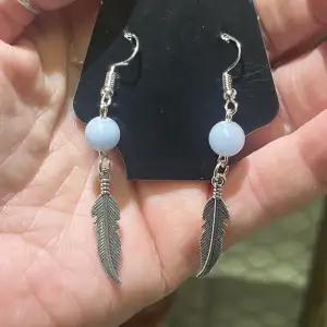 Nya handgjorda örhängen med pärlor av blå kalcit och fjädrar. Nickelfri metall. Blå kalcit sägs verka lugnande, ca 3-4 cm