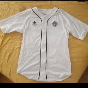 Baseball skjorta från Adidas - Lent och silkigt material. Sitter lätt på kroppen. Köpt på mans sidan så lite oversized på. Använd fåtal gånger. 