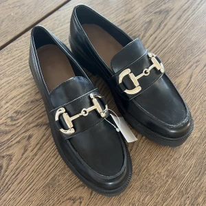 Loafers  - Säljer ett oanvända loafers ifrån hm med guldspänne framtill. Prislapp sitter kvar  Nypris 299:- nu 150:-