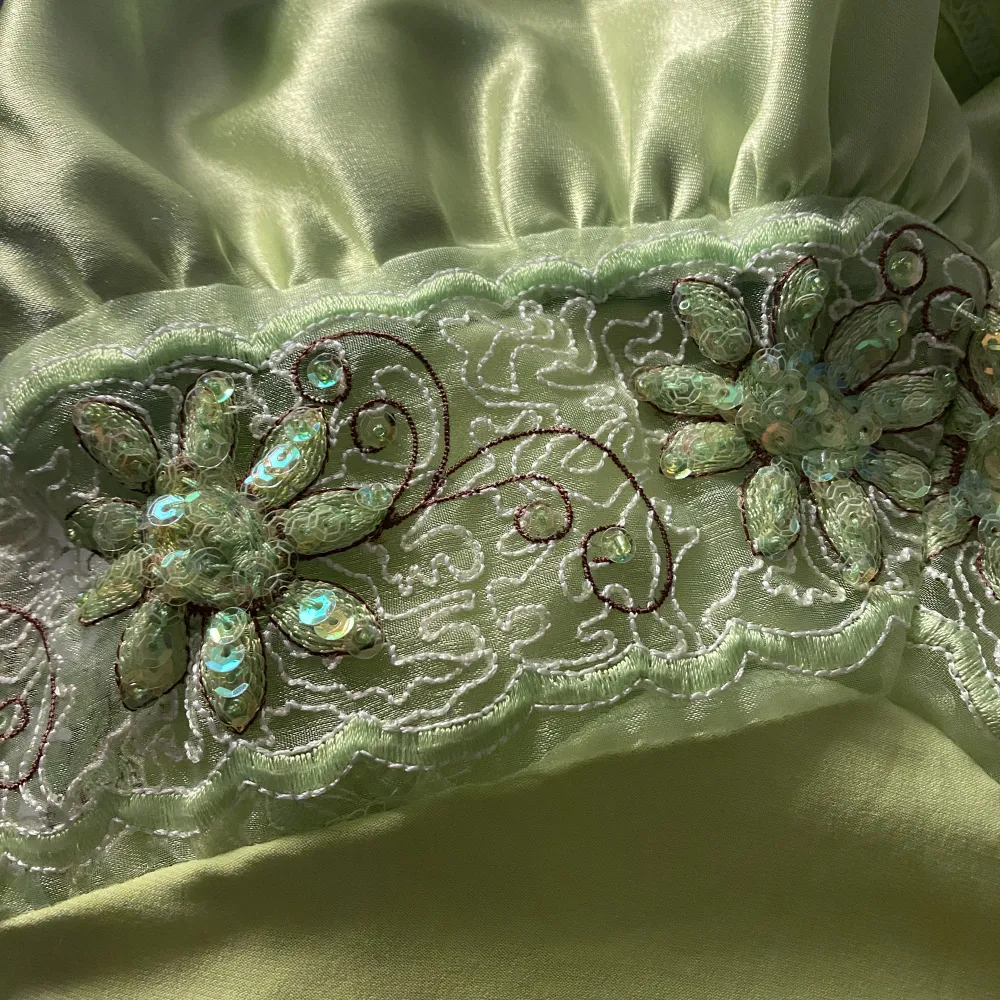 Superfin långklänning i en stark ljusgrön färg med en genomskinlig spetsdetalj under bysten. Spetsen är även dekorerad med små paljetter och sträcker sig runt midjan.. Klänningar.