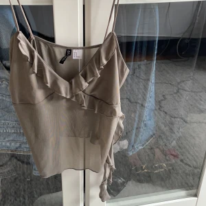 Grått linne med volang  - Super snygg och har som typ volang snören som hänger. Endast använd en gång. Säljer även en likadan i svart💓