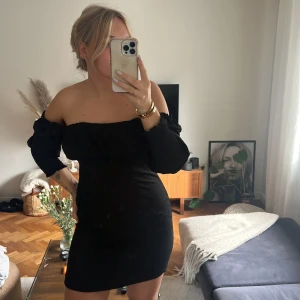 Svart klänning  - En svart klänning man kan ha på 2 sätt! Öppen i ryggen, tillkommer ett extra band man kan sy fast om man vill fästa den med ett till snöre över ryggen. Dragkedja på sidan och den är i ett tunt lite glansigare tyg! Använd en gång, jättefint skick! Strl 38🖤