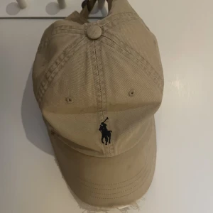 Ralph Lauren keps  - Beige Ralph lauren keps.  Välanvänd & lite skadad på fronten (därav priset) skriv för fler bilder 👍🏼