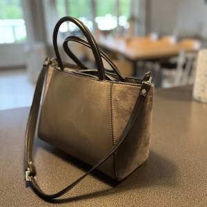 En mindre handväska i mocka och skinn-material (fake)