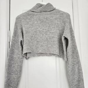 Stickad topp - Stickad topp med turtleneck och croppad passform💕 supermysig att slänga över en bikini efter ett svalt bad! Lite nopprig men i övrigt i bra skick. Finns ingen lapp med stl i tröjan men sitter ungefär som en S