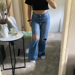 De perfekta blåa jeansen! - Säljer ett av mina favort jeans!! Dom har den perfekta blå färgen och snygga hål på knäna! Kommer tyvärr inte till användning längre:/ Jeansen har också en perfekt längd, jag är 169 och dom går lite under min häl.