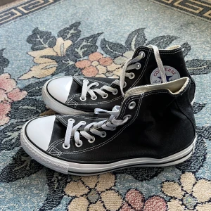 Svarta converse - Svarta high top converse all star stl 40 Utmärkt skick, använd ca 5 ggr. Svag rosa rand längs sidan av högra skon. *försäljning pågår fram till 29 juli då jag flyttar och måste tömma min garderob!!*