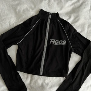 Topp med reflexiva detaljer  - Cool tight croppad tröja. Dragkedja som döljs av reflex detalj. Använd 1 gång. Passar som XS