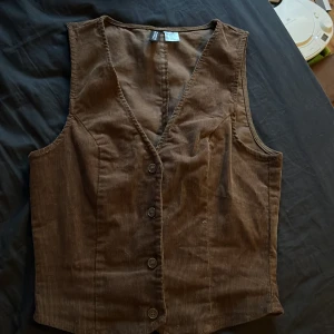 Brun topp - En brun ”korsett” topp med knappar i fram som man kan spänna själv, det har blivit för liten för mig och säljer den därför, inte så mycket använd. Manchester tyg.