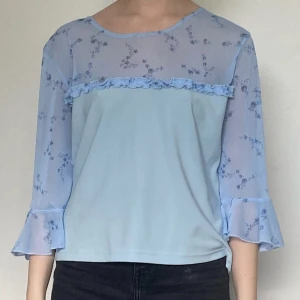 Turkos tröja med blommor och volang - Jättefin tröja med blommor och volang, nästan aldrig använd Storlek: I tröjan står det storlek XL, men skulle säga att den sitter som en S/M