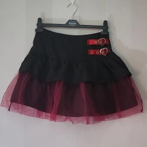 Kjol - Kjol med rosa tyll i nedre delen och röda spännen vid sidan.