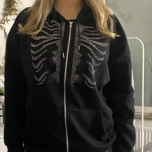 Black skull hoodie - Svart zip up med skelett rhinestones på, skit snygga detaljer på. Den är storlek M och är bekväm