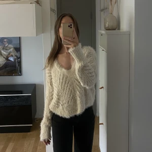 Stickad tröja  - Stickad tröja med djup urringning. Creamvit/ljusbeige färg, stl: XS (passar XS-S), fint skick. 