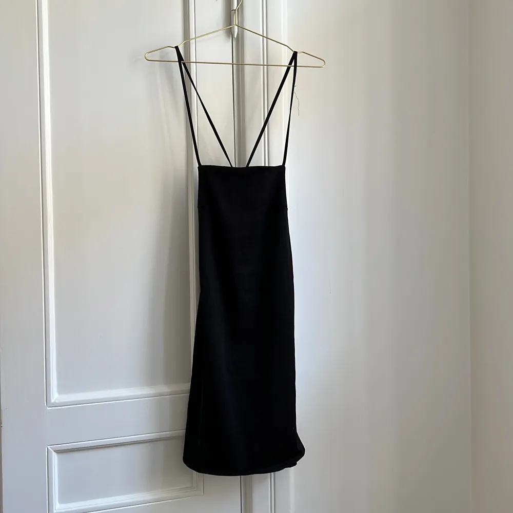 En svart miniklänning ifrån hm som går att knyta baktill för att få en bättre passform . Klänningar.