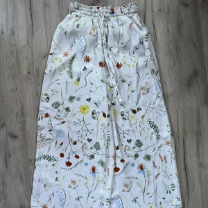 Blommiga byxor  - Svala linne byxor med extra tyg runt höften. Oanvända. Långa i bene för sin storlek.