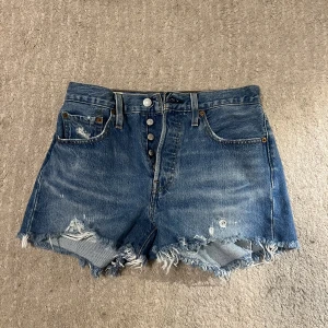 501 Levis jeansshorts - MINA FAVORITSHORTS GENOM TIDERNA. Hade inte sålt om de passade. Blåa jeansshorts med slitningar och asbra passform. De är från Levis i modell 501. Är osäker på storlek. 
