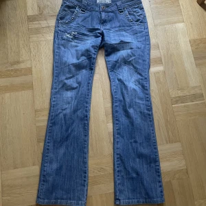 Lågmidjade jeans - Lågmidjade jeans med fina detaljer. Säljer för att de tyvärr är för stor på mig💙 innerbenslängden 84 cm och midjemåttet är 43-44 cm