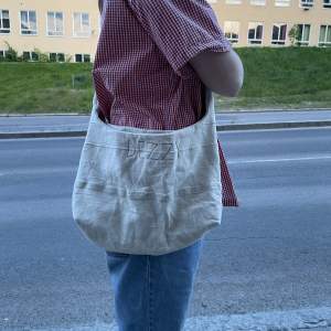 En handsydd väska gjord av återanvänt segondhand-tyg med fickor av Lars Wallin tyg❤️