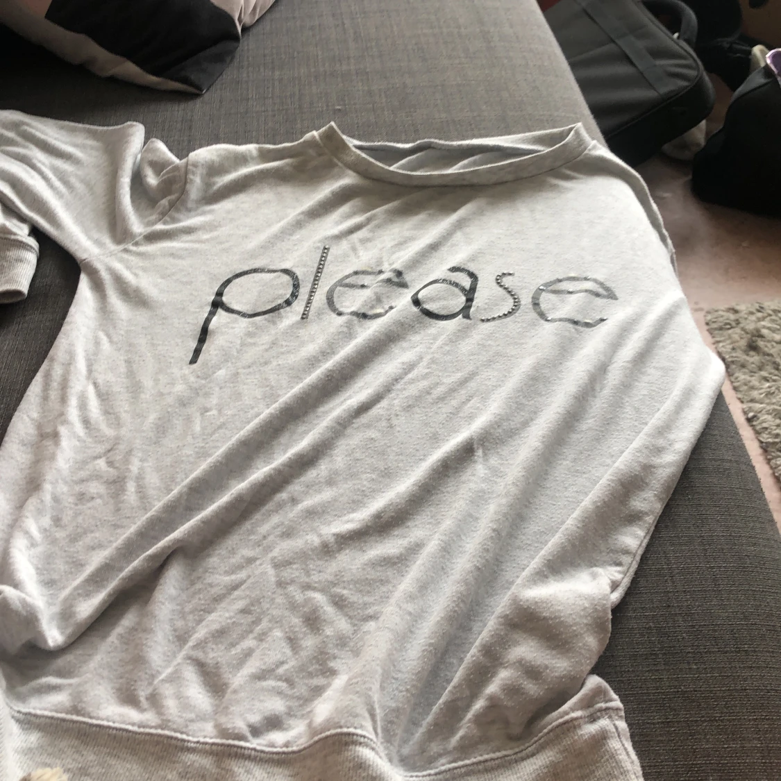 Grå jumper med texten ”please”