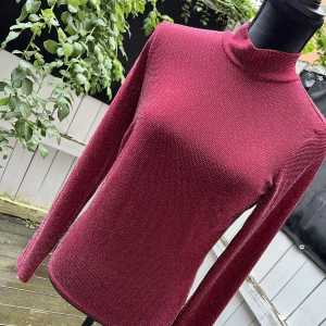 Glittrig polotopp från Nelly - Charmig glittrig polotopp från Nelly.  Färg (mörk röd)   Ej använd