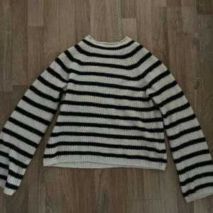 Randig stickad tröja - Säljer min mbyM stickade tröja, den är vit med svarta/mörkblå ränder. Nypris var ca 1000 kronor. Det är äckta alpacka ull i den, typ aldrig andvänd heller❤️