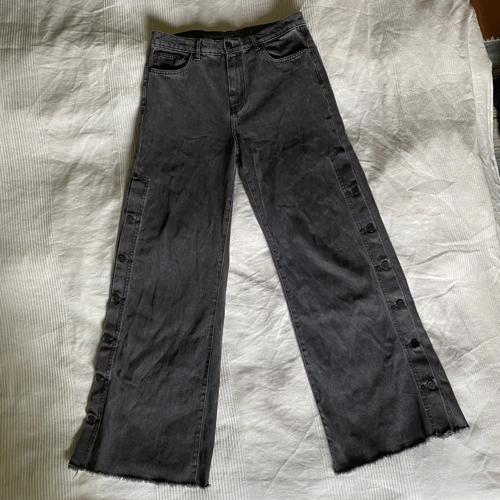 Jättecoola svarta/gråa vida jeans som går att knäppa upp med knappar på sidorna. Stor att storleken är L men passar perfekt low waist på mig som brukar ha s. Midja: 39cm. Skriv om du har fler frågor!. Jeans & Byxor.