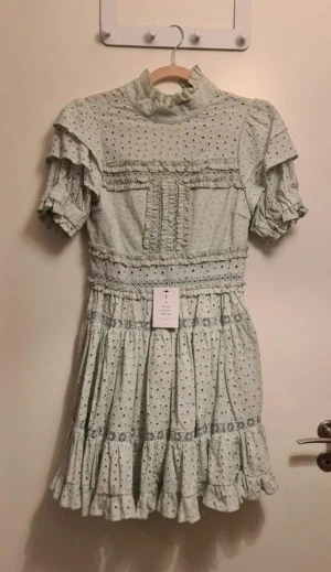 Klänning från By Malina - Klänning från By Malina  Spetsklänning med puffärmar. Kortärmad, fodrad kjoldel, försluts med knappar i ryggen. Storlek: Small Klänningen är aldrig använd, lappar kvar. Säljer vidare då den ej passade. Nypriset då var 2000kr.  