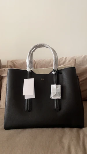 Hugo Boss  - Hugo Boss dam hand väska medel stor. Har ingen användning för denna väska dånjag vunnit på jobbet. Men tänker någon annan kan få god nytta utav den. Den har tre fack perfekt för laptop och annat tillbehör.  Önskar fler bilder kan ni bara hojta till.  