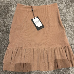 glittrig kjol - Säljer en otroligt söt kjol med volang och glitter i smutsrosa från NAANAA i storlek XS✨Aldrig använd, prislapp sitter kvar! Nypris 499kr, säljer för 150kr + frakt!