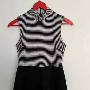 Byxdress - Byxdress med enkel svart underdel och randig topp. Utan ärm och halvpolo. Ger en snygg midja. 