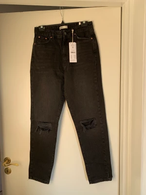Dagny mom jeans - Svarta mom jeans från gina med hål i knäna, helt oanvända med lappen på