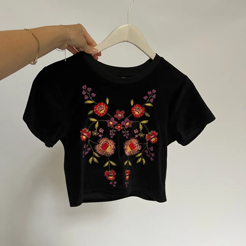 croppad t-shirt i sammet med broderade blommor. använd några få gånger!. Toppar.