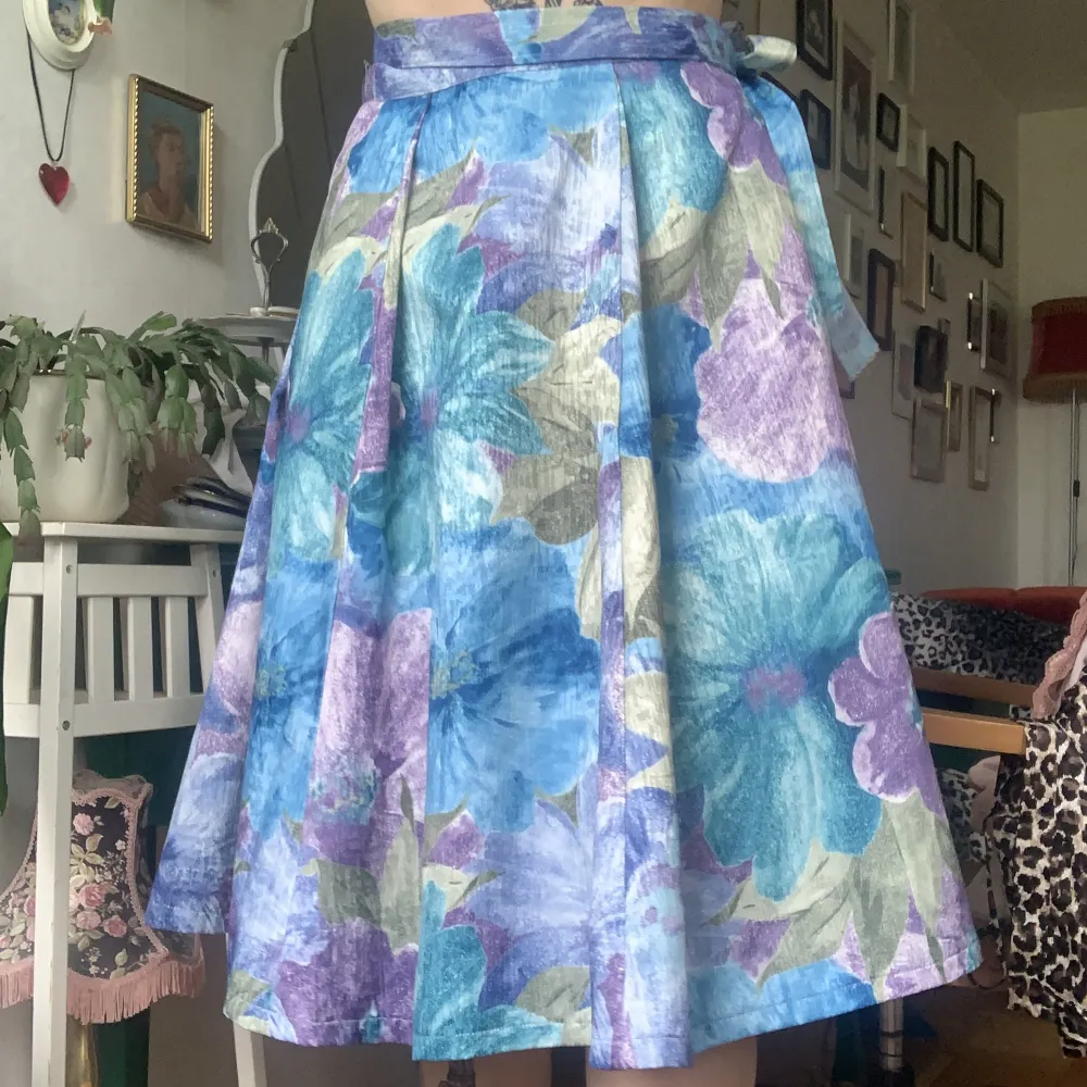 Handsydd vintage omlottkjol med lila och blåa blommor. Den är omlott med mycket tyg så man kan anpassa storleken mycket . Kjolar.