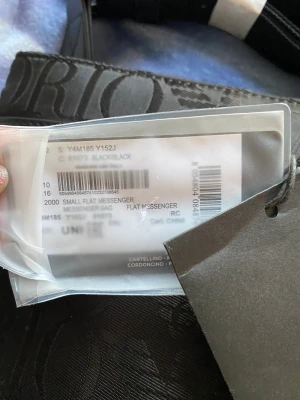 EA7 väska  - Emporio Armani platt axelrem i hela Jacquard -tyget. Ficka framtill med dragkedja. Justerbar logotyp axelrem. Interiör med två fickor, en med dragkedja. Handla axelstängning med zip. Dimensioner: 23,5 x 23,5 x 4 cm.  Nyköpt, med kartong och prislapp på.  