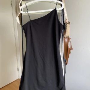 Klänning NA-KD - Svart assymetrisk klänning från NA-KD. I väldigt bra skick, använd 1 gång. Kan både posta och träffas upp i Stockholm :) kan även skicka bild på hur klänningen sitter på vid behov 