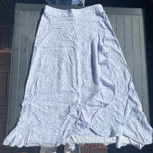 Långkjol - Det en blå långkjol med vita blommor. Det är en volangkjol. Den är även väldigt skön samt luftig. Prefekt inför sommaren när man vill ha lite längre kjolar