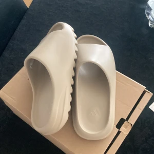 Yeezy slide warm sand  - Säljer dessa sköna tofflor. Endast testade. Storlek 43.  1200, pris kan diskuteras.  Kontakta mig vid intresse. 